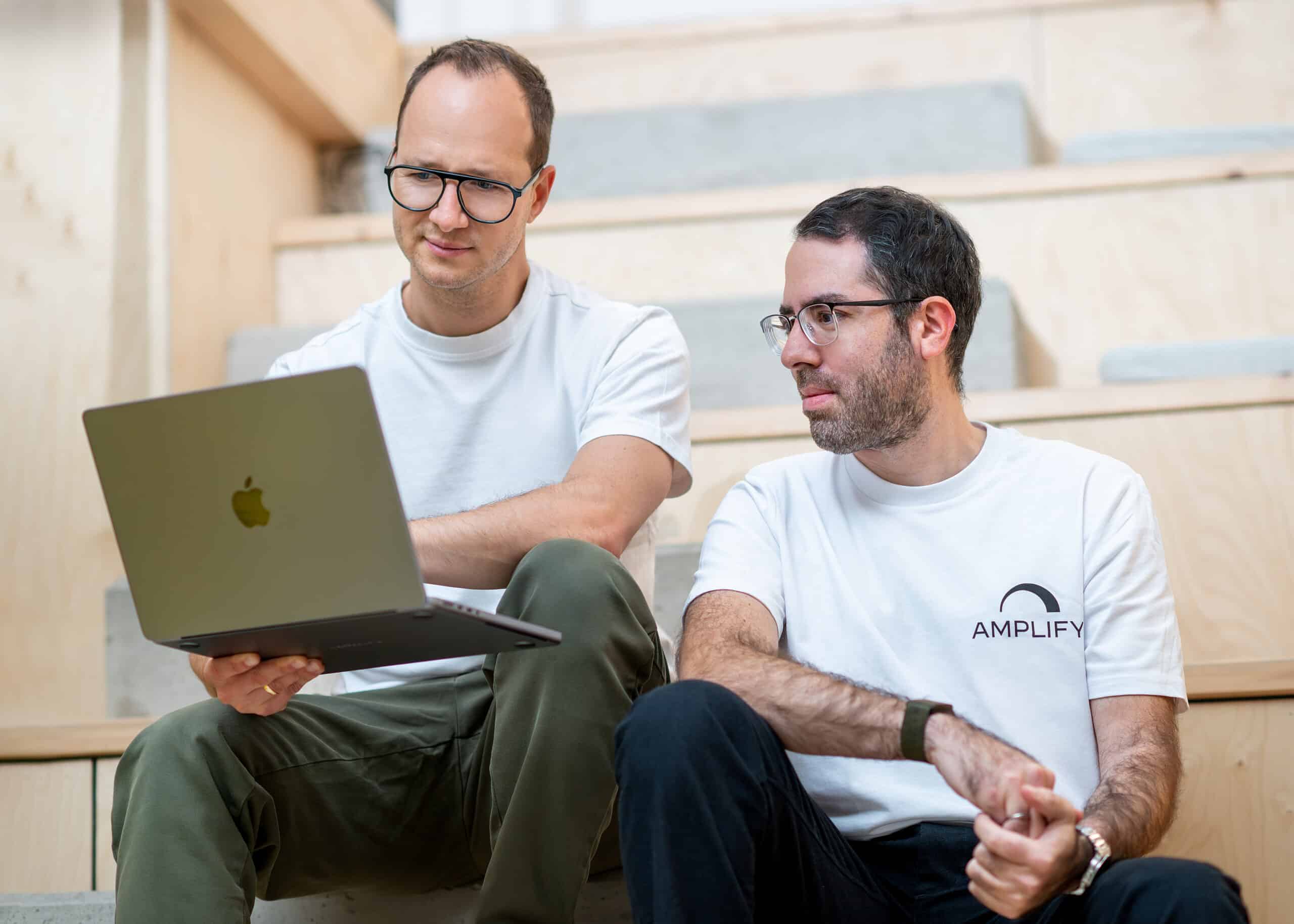 Two men collaborating on a laptop, discussing the future of mobility and eMobility solutions.