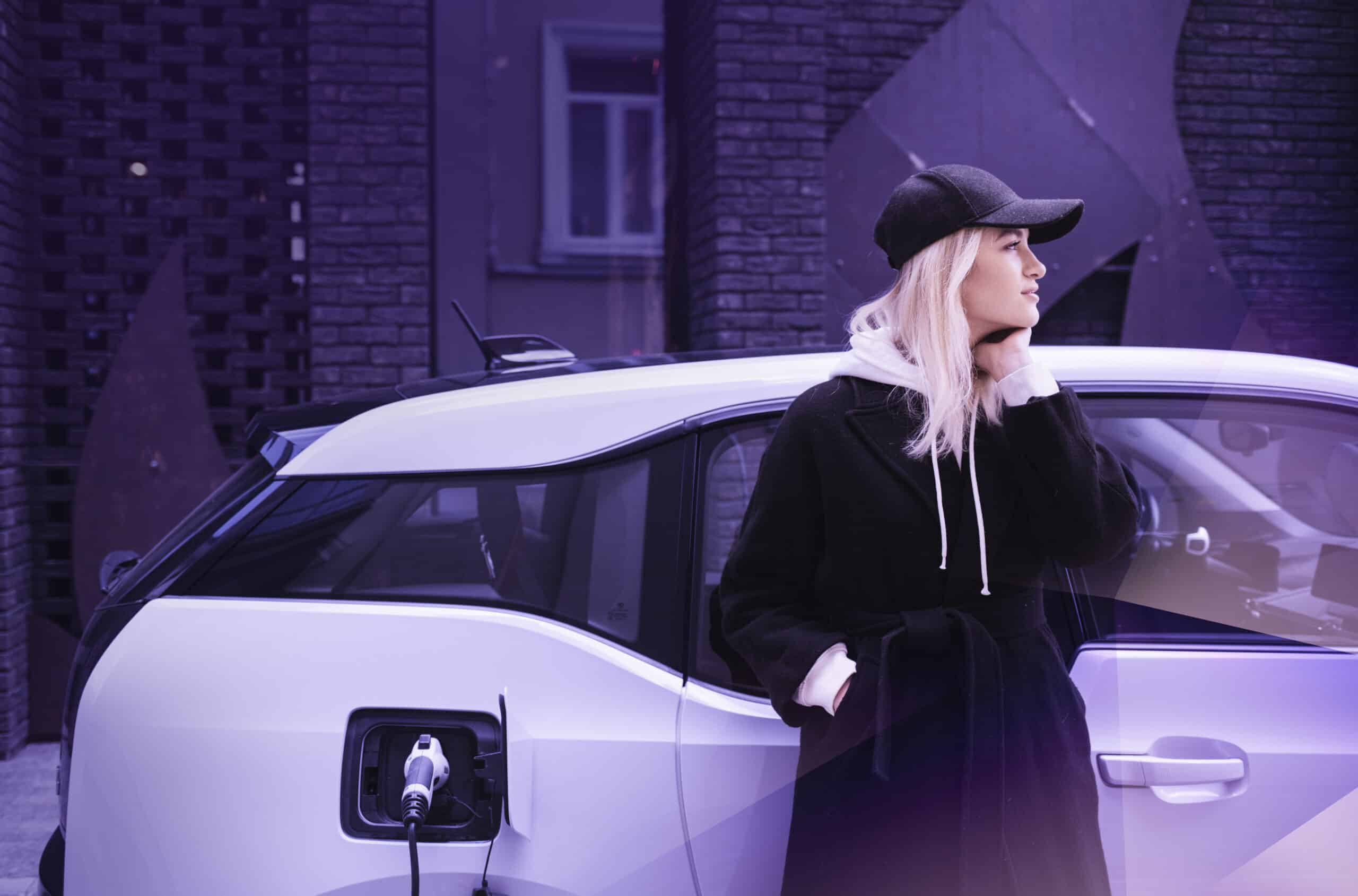 Woman stands by an electric vehicle, highlighting eMobility and EV-Charging as the future of mobility.