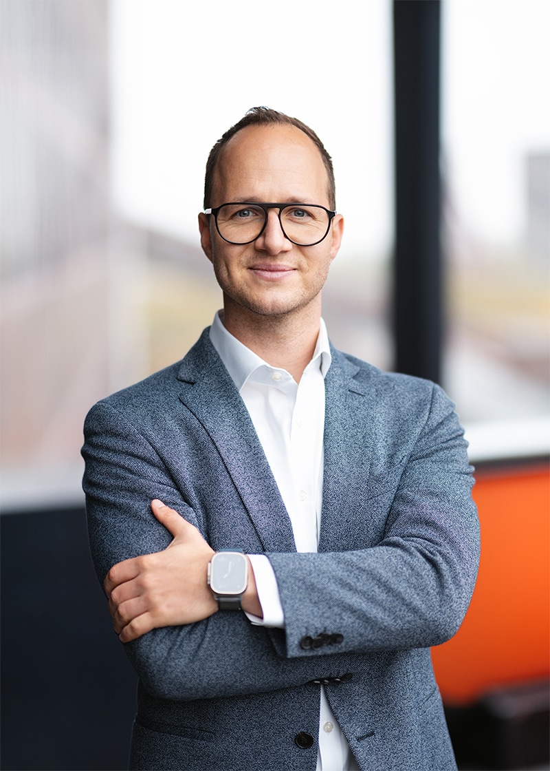 Geschäftsmann im Anzug, der die Zukunft der Mobilität und die Fortschritte im Bereich der Elektromobilität repräsentiert.