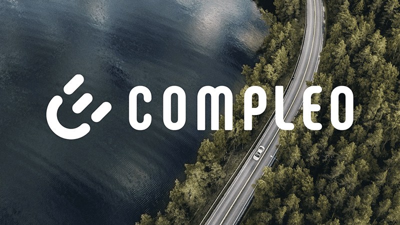 Compleo logo over aerial of road by water and forest, highlighting eMobility and the future of mobility trends.
