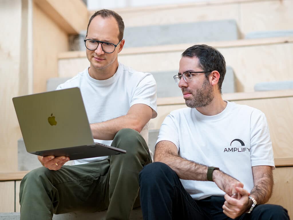 Zwei Männer arbeiten gemeinsam an einem Laptop und erforschen eMobility-Lösungen für die Zukunft der Mobilität.