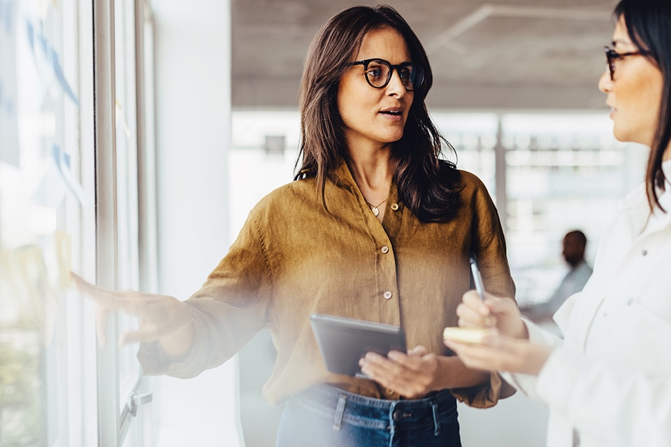 Frauen diskutieren in einem modernen Büro über E-Mobilitätspläne und heben dabei die Zukunft der Mobilitätsinnovation hervor.