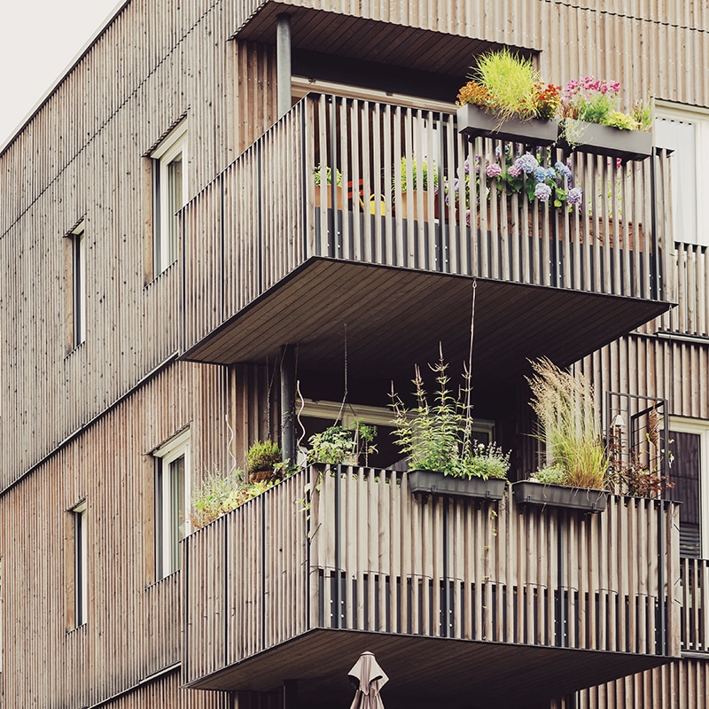 Modern wooden building with green balcony plants, symbolizing sustainability and the future of mobility.