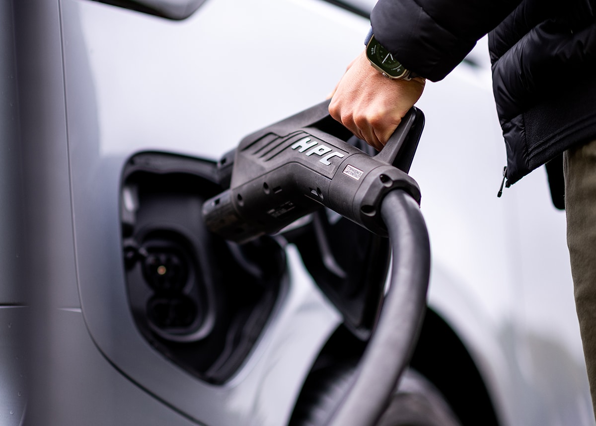 Person, die ein HPC-Ladegerät für Elektrofahrzeuge verwendet, zur Veranschaulichung des Ladens von Elektrofahrzeugen und der Zukunft der Mobilität.